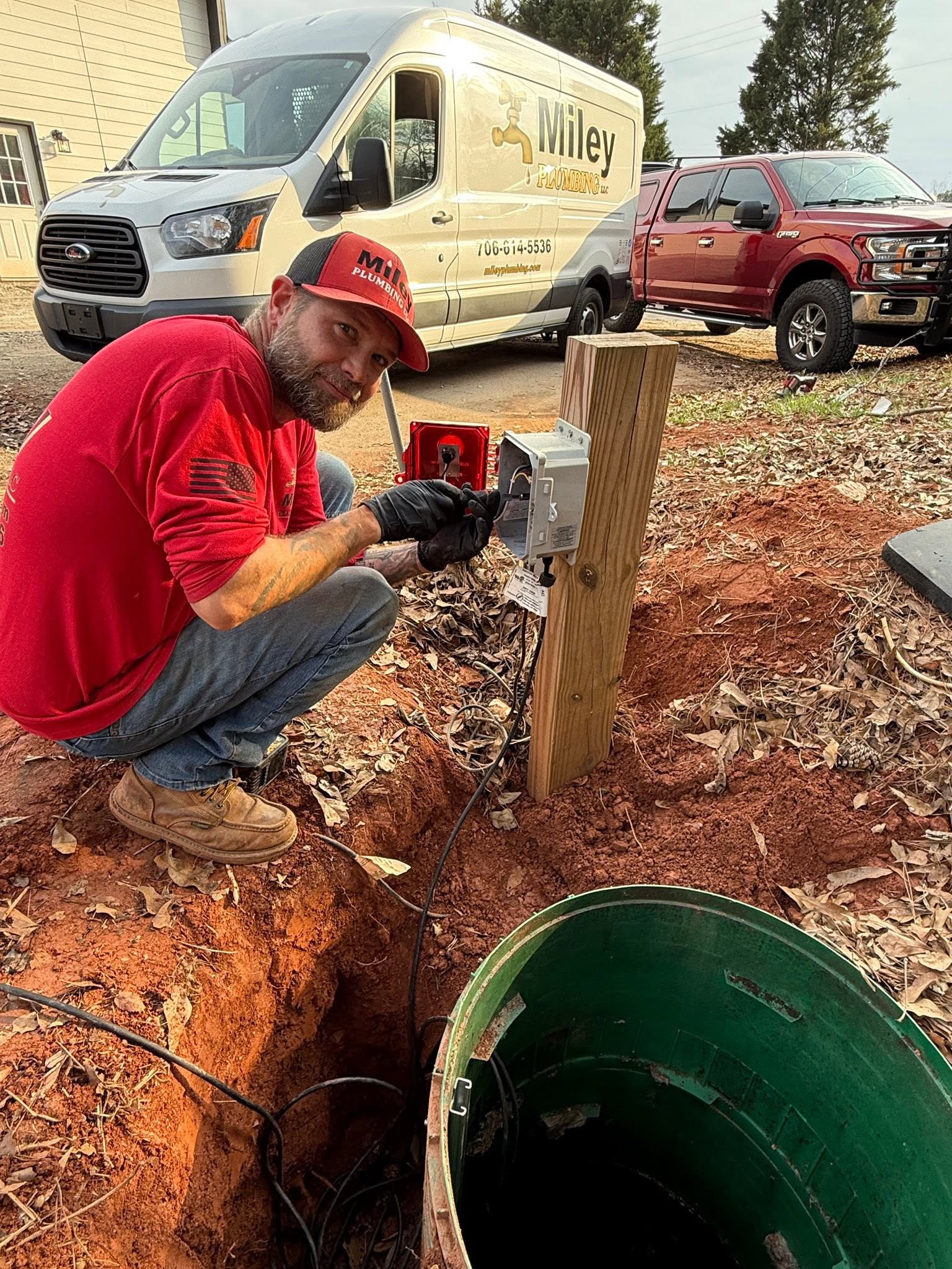 Plumber wiring an alarm panel for a sewage pump basin