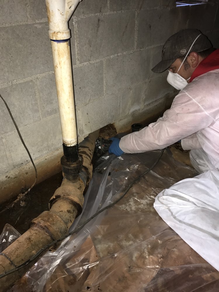 Plumber replacing a cast iron drain line in a crawl space